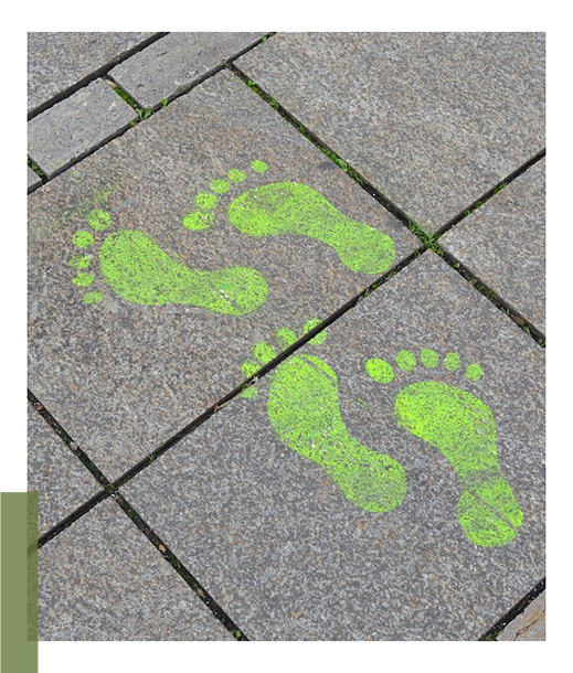 grüne Fußabdrücke auf Asphalt