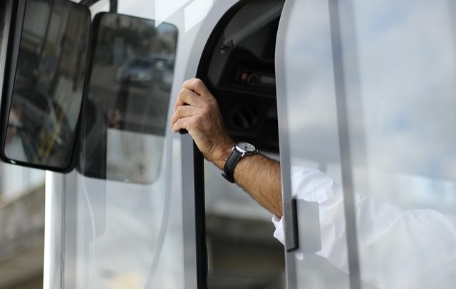 Arm mit Armbanduhr greift aus geöffnetem Fenster eines weißen Fahrzeugs