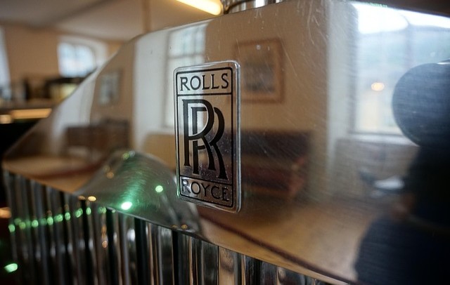 Nahaufnahme des silbernen Rolls-Royce-Logos auf der Motorhaube eines Fahrzeugs.