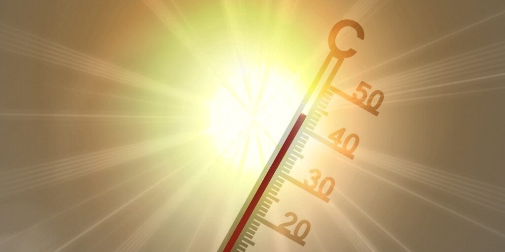 Thermometer bei etwa 45 Grad Celsius, umgeben von gelb-rotem Lichtschein – visuelle Darstellung extremer Hitzeereignisse als Folge des Klimawandels.