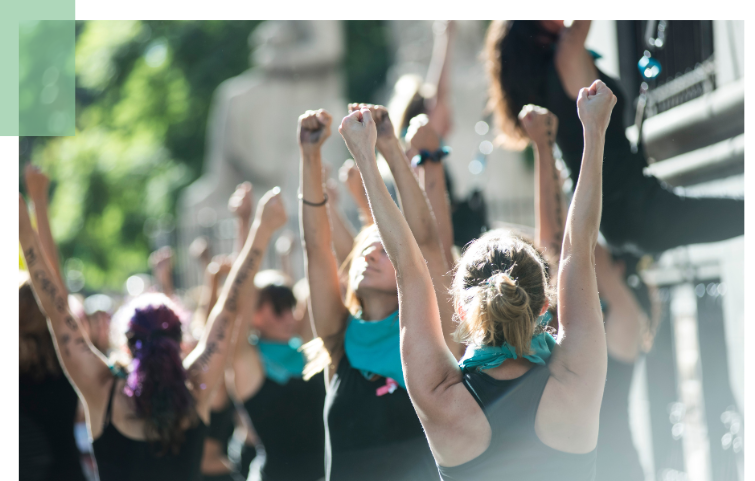 Gruppe von Menschen, im Freien, gucken mit erhobenen Fäusten nach oben.