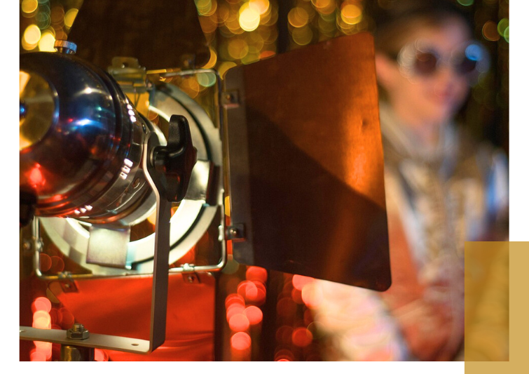 Headlights in front of a girl, colorful blurred lights in the background.