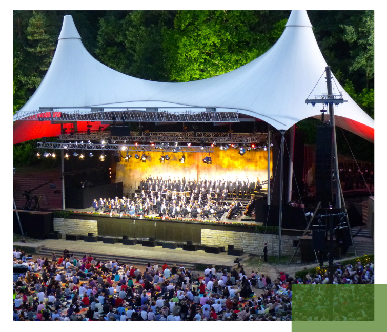 An open-air concert set in a natural landscape, emphasizing the value of protecting such environments under SDG 15.