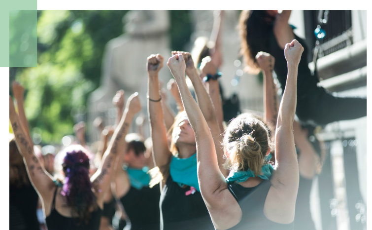 Group of people, outdoors, looking up with raised fists.